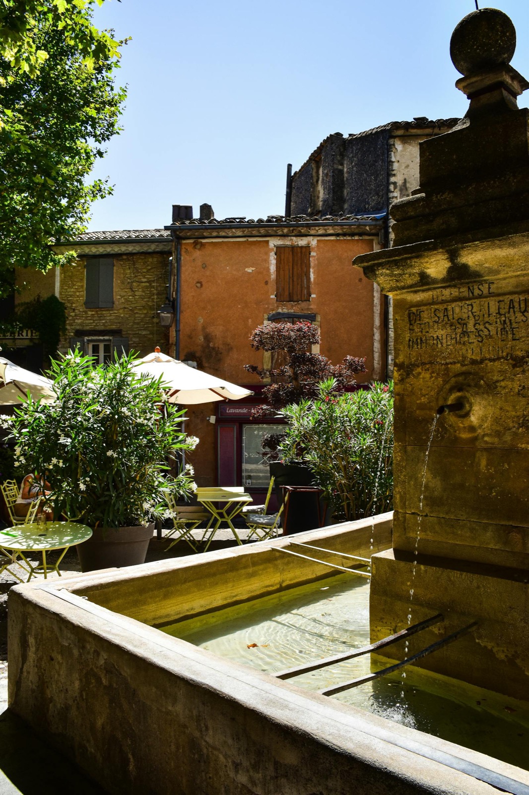 Fontaine ancienne et terrasse sous platanes en Provence
